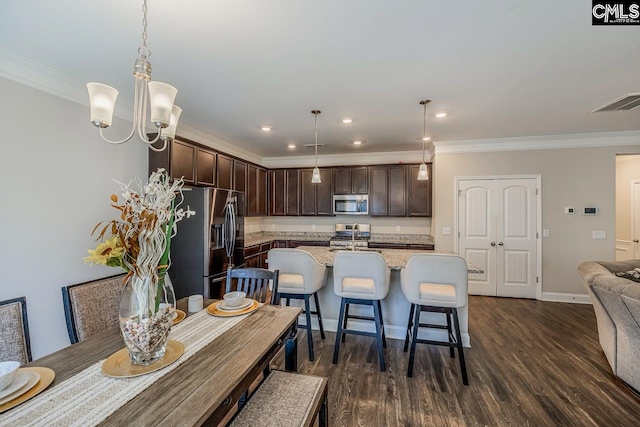 kitchen featuring decorative light fixtures, stainless steel appliances, a center island with sink, and dark hardwood / wood-style flooring