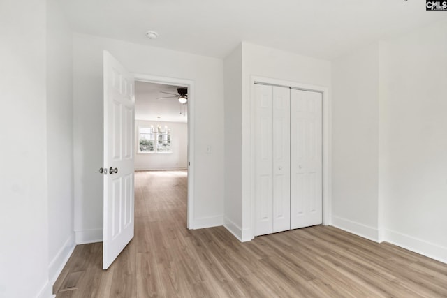 unfurnished bedroom featuring a closet, an inviting chandelier, and light hardwood / wood-style floors