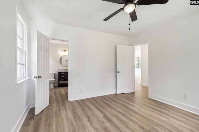 unfurnished bedroom with light wood-type flooring, ceiling fan, and connected bathroom