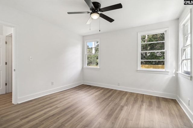 spare room with light wood-type flooring, a wealth of natural light, and ceiling fan