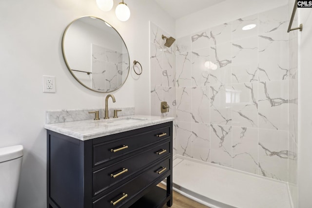 bathroom with toilet, vanity, wood-type flooring, and tiled shower