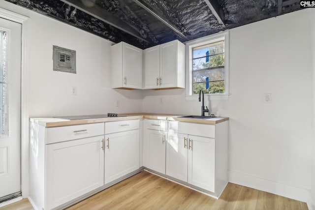 kitchen featuring white cabinets, sink, black electric stovetop, and light hardwood / wood-style flooring