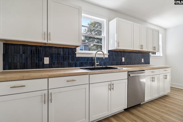 kitchen featuring butcher block countertops, backsplash, sink, white cabinets, and dishwasher