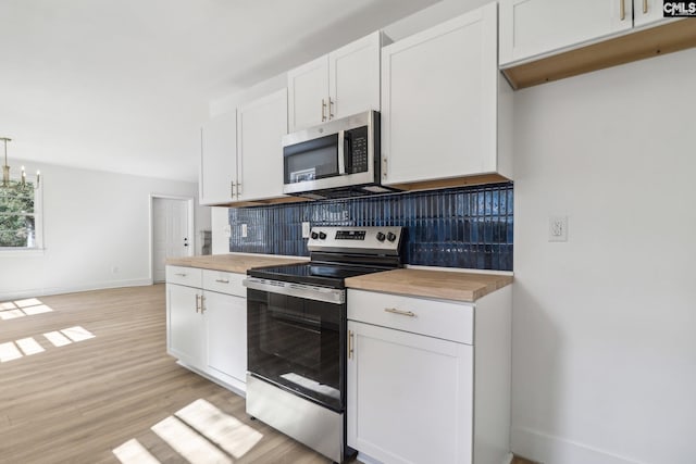 kitchen with white cabinetry, light wood-type flooring, appliances with stainless steel finishes, and decorative light fixtures