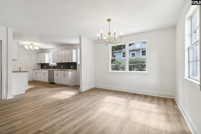 kitchen featuring dishwasher, pendant lighting, light hardwood / wood-style floors, and white cabinets