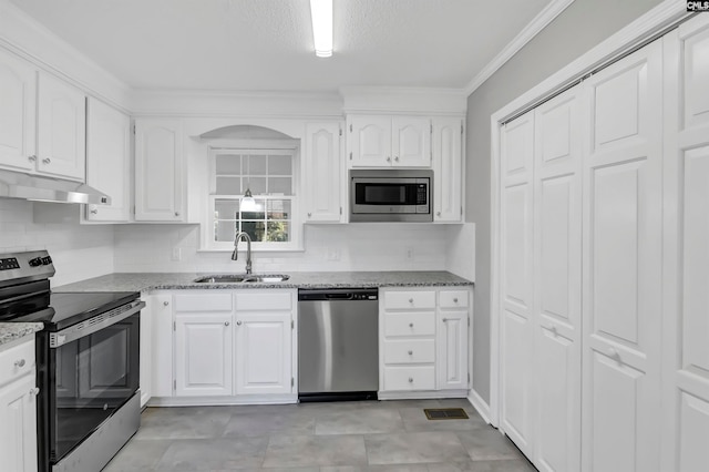 kitchen featuring appliances with stainless steel finishes, white cabinets, sink, and light stone counters