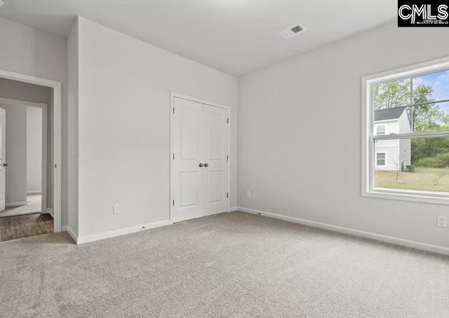 carpeted empty room featuring visible vents and baseboards