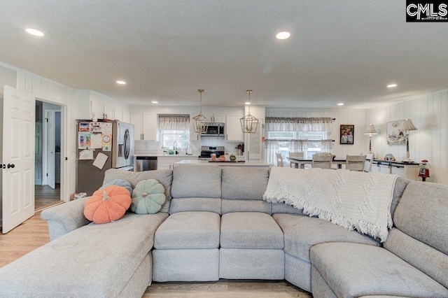 living room with light hardwood / wood-style floors, a textured ceiling, and sink