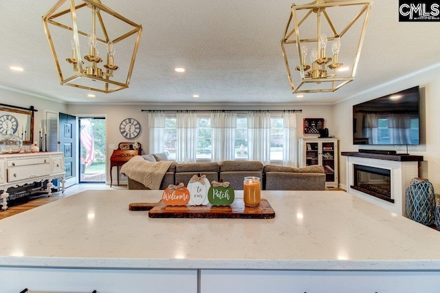 kitchen featuring a textured ceiling, a barn door, hardwood / wood-style flooring, light stone countertops, and crown molding