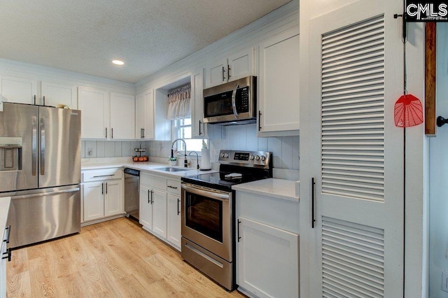 kitchen featuring white cabinetry, light hardwood / wood-style floors, appliances with stainless steel finishes, and sink