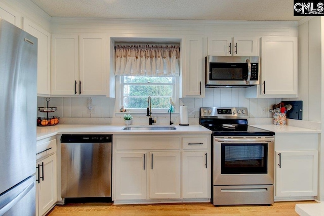 kitchen with tasteful backsplash, sink, light hardwood / wood-style floors, stainless steel appliances, and white cabinets