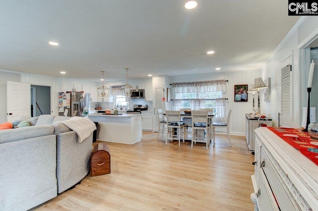 living room with crown molding, a textured ceiling, and light wood-type flooring