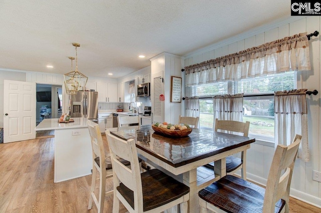 dining space featuring a chandelier, sink, crown molding, and light wood-type flooring