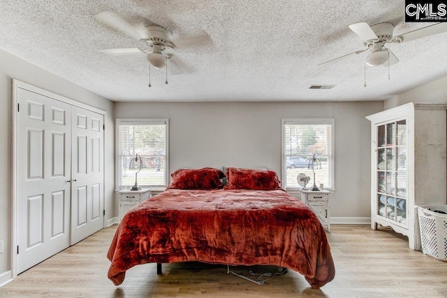 bedroom with multiple windows, light hardwood / wood-style floors, and ceiling fan