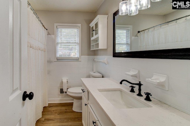 bathroom with toilet, hardwood / wood-style flooring, vanity, and tile walls