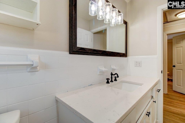 bathroom featuring toilet, vanity, wood-type flooring, and tile walls