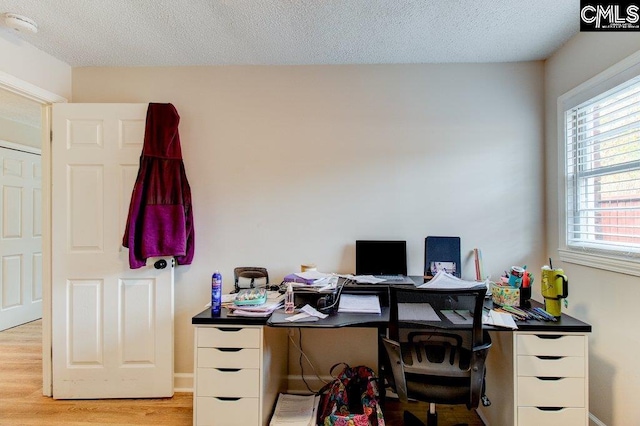 home office with a textured ceiling and light hardwood / wood-style flooring