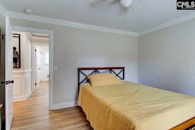 bedroom with light hardwood / wood-style floors, ornamental molding, a textured ceiling, and ceiling fan