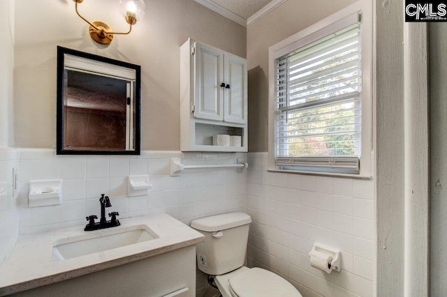 bathroom featuring vanity, toilet, ornamental molding, and tile walls