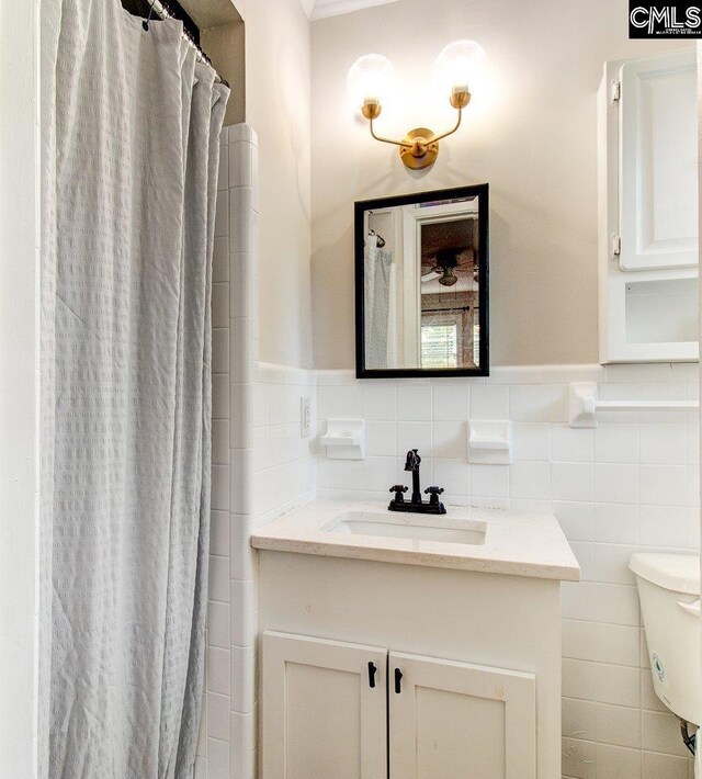 bathroom with vanity, toilet, tile walls, and curtained shower