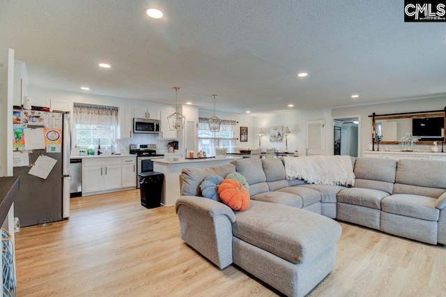 living room featuring sink, a textured ceiling, and light hardwood / wood-style floors