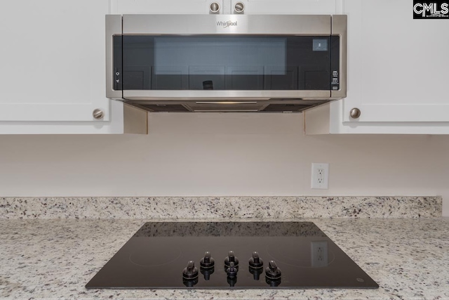 details with light stone countertops, black electric cooktop, and white cabinets