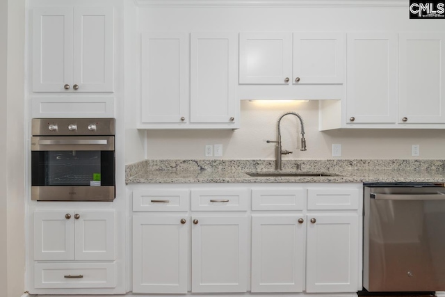 kitchen with white cabinetry, light stone countertops, appliances with stainless steel finishes, and sink