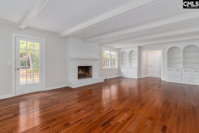 unfurnished living room with crown molding, hardwood / wood-style floors, a healthy amount of sunlight, and built in shelves