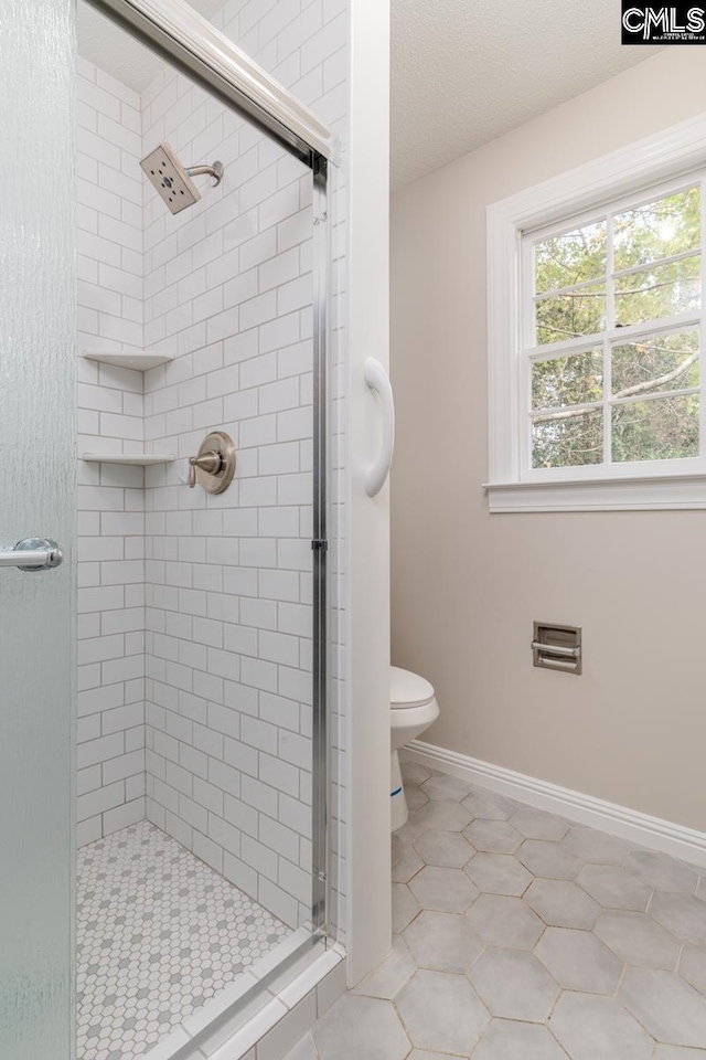 bathroom with tile patterned floors, a textured ceiling, toilet, and walk in shower