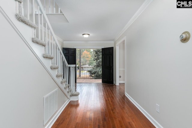 foyer entrance featuring ornamental molding and dark wood-type flooring