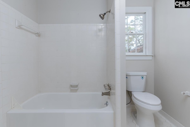 bathroom with toilet, tile patterned flooring, and tiled shower / bath