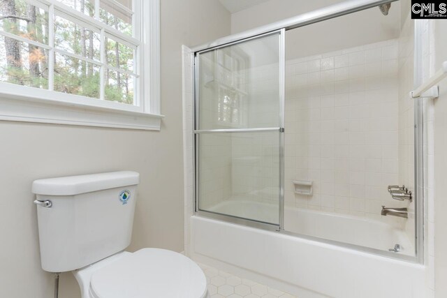 bathroom featuring toilet and combined bath / shower with glass door