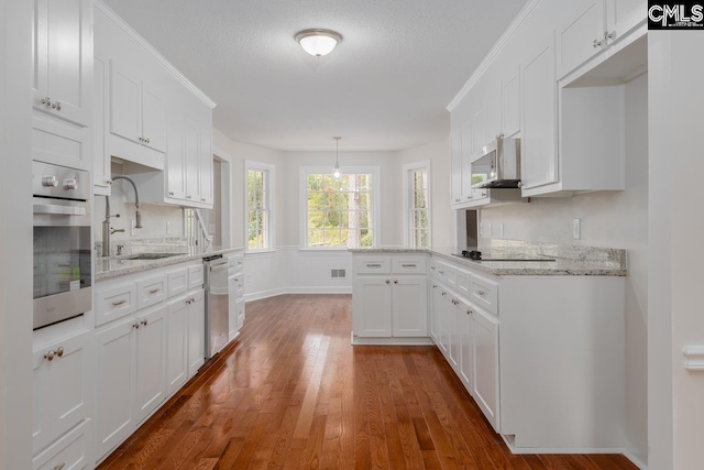 kitchen with sink, white cabinetry, stainless steel appliances, pendant lighting, and dark wood-type flooring