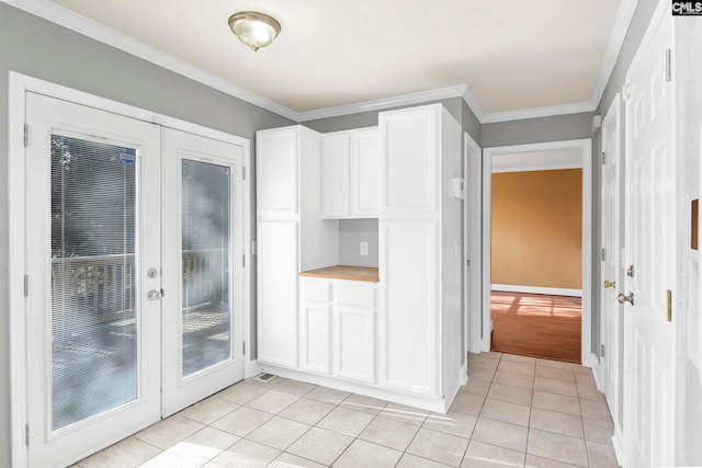 kitchen with white cabinets, french doors, light tile patterned flooring, and crown molding