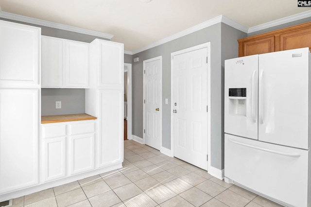 kitchen with white fridge with ice dispenser, white cabinets, light tile patterned flooring, and crown molding