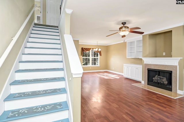 stairway featuring ornamental molding, hardwood / wood-style floors, and ceiling fan with notable chandelier