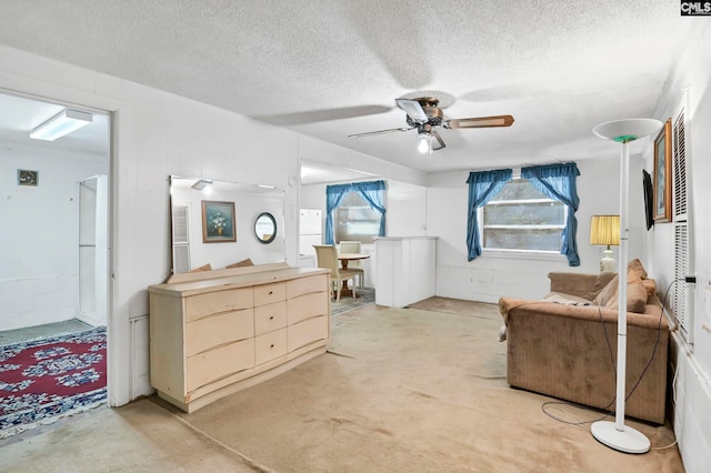 living area with a textured ceiling and ceiling fan