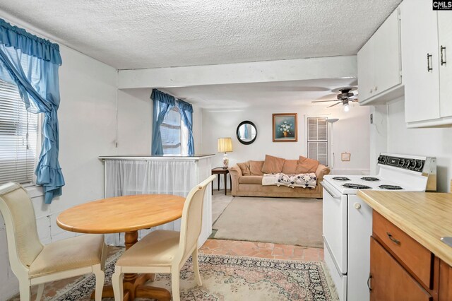 kitchen with white cabinetry, light carpet, white range with electric stovetop, ceiling fan, and a textured ceiling