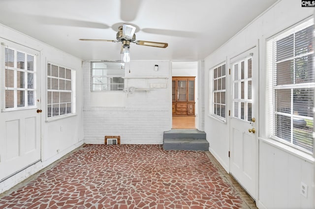 unfurnished sunroom featuring ceiling fan