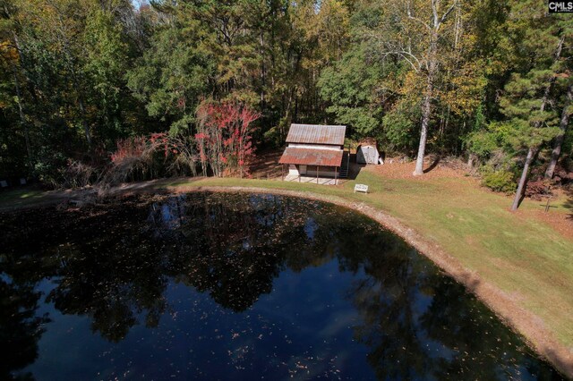 view of pool featuring a water view, a yard, and a storage unit