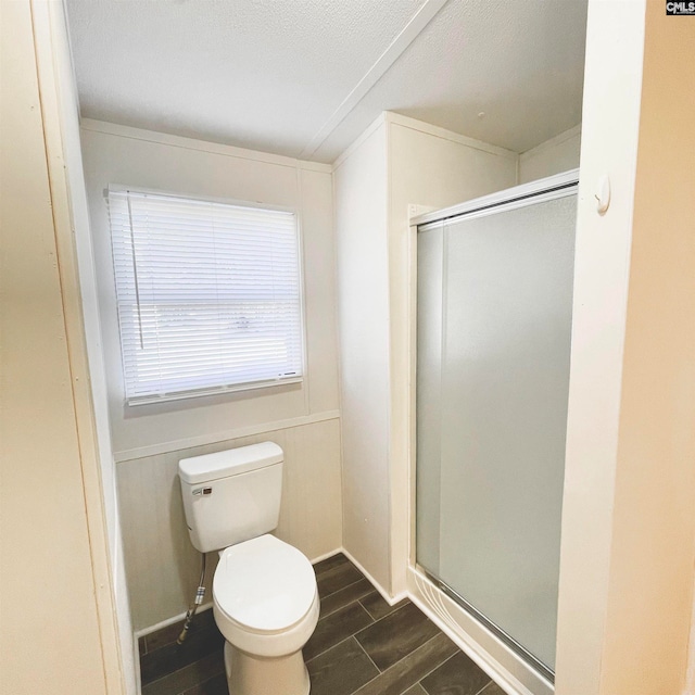 bathroom with hardwood / wood-style floors, an enclosed shower, a textured ceiling, and toilet