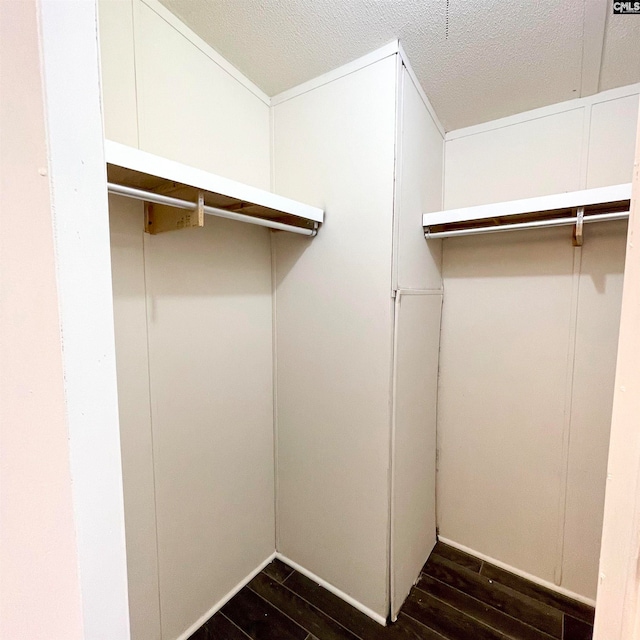 walk in closet with dark wood-type flooring