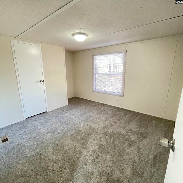 empty room with a textured ceiling and carpet flooring