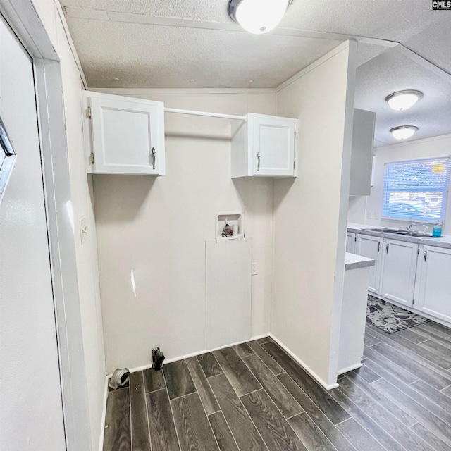 laundry room featuring dark hardwood / wood-style flooring, cabinets, a textured ceiling, sink, and hookup for a washing machine