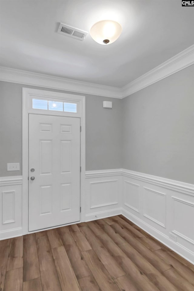 foyer entrance with hardwood / wood-style floors and crown molding