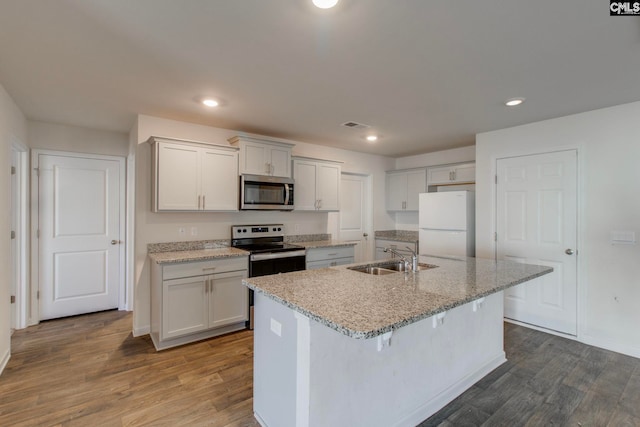 kitchen featuring stainless steel appliances, wood-type flooring, a center island with sink, white cabinets, and sink