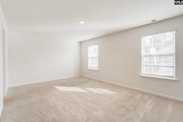 spare room featuring light colored carpet and a healthy amount of sunlight