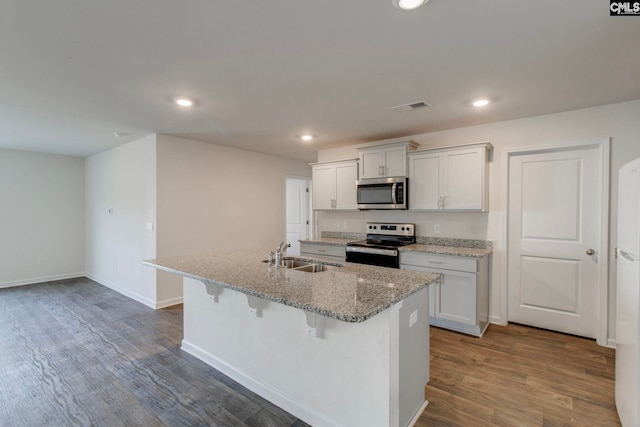 kitchen with dark wood-type flooring, a center island with sink, white cabinets, sink, and appliances with stainless steel finishes