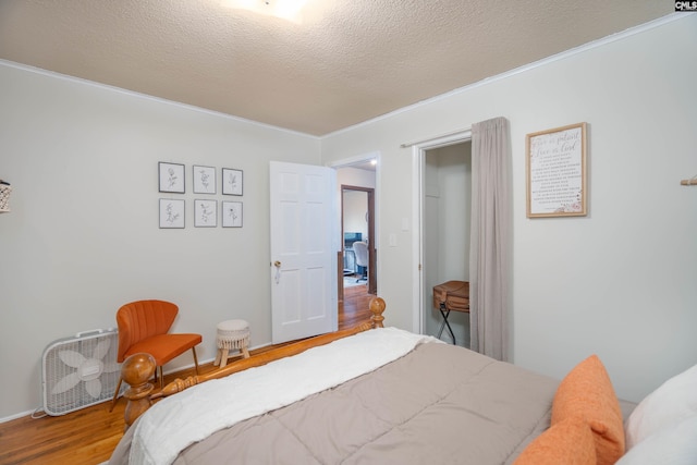 bedroom with hardwood / wood-style floors, a textured ceiling, and ornamental molding