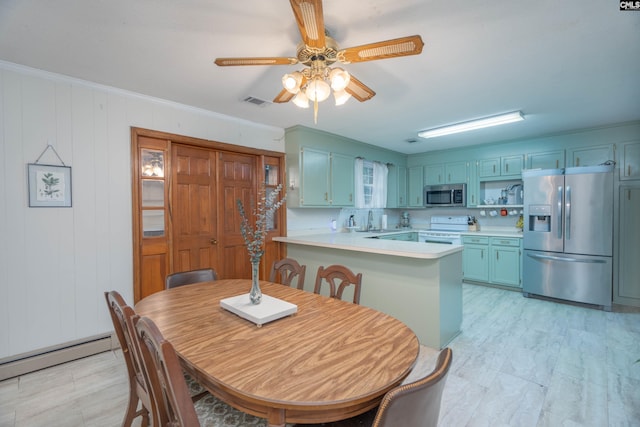 dining room featuring crown molding, wooden walls, sink, a baseboard radiator, and ceiling fan